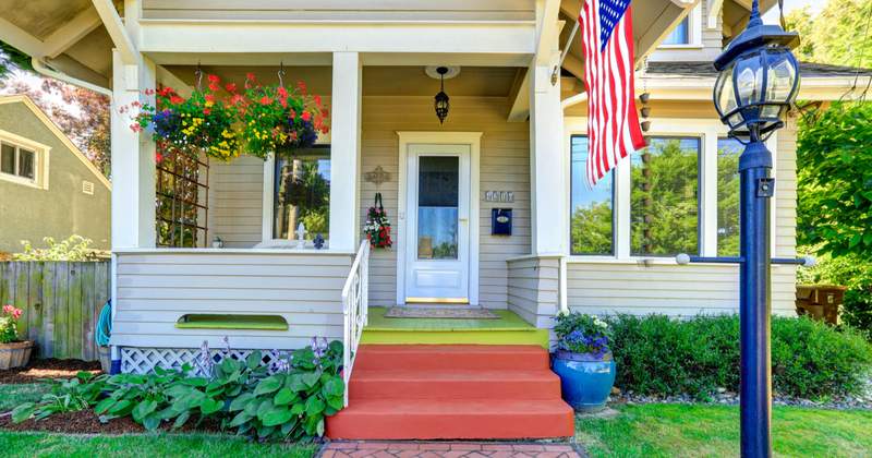 Pretty front porch with flower baskets and American flag